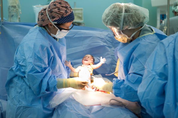 A baby being born by cesarean section, which might be the safest way to go with a breech baby. 