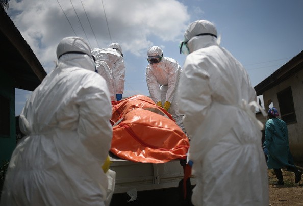 Workers handling the body of an Ebola victim in LIberia. Health restrictions have clashed with funeral practices in neighboring Guinea.
