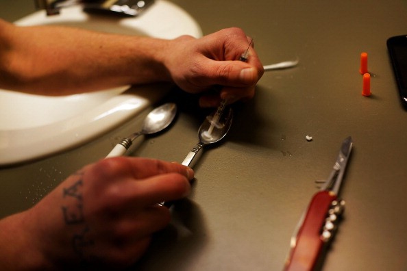 An addict prepares an injection of heroin. 