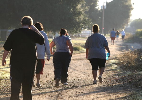 Teens who are overweight are shown walking for exercise. A study has found that weight screening programs in schools may not help teens lose weight. 