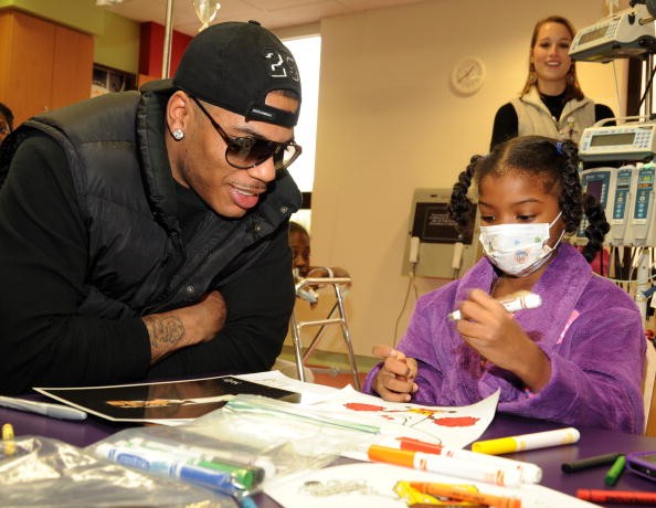 Hip hop star Nelly visiting a child with cancer in the hospital. /children who survive cancer may face long-term problems.