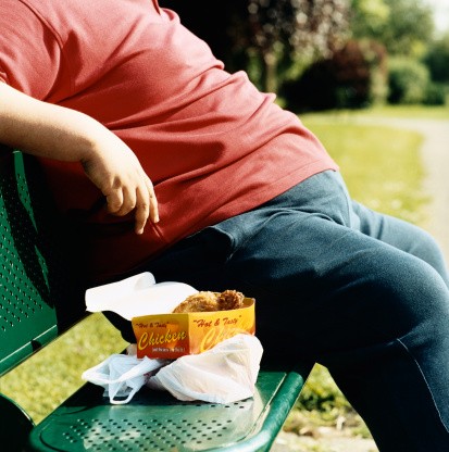 Overweight man sitting on park bench