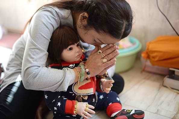  Doll collector Mananya Boonmee holding a 'luuk thep' (child angel) doll as she offers prayers during a religious ceremony at the Bangchak Buddhist Temple