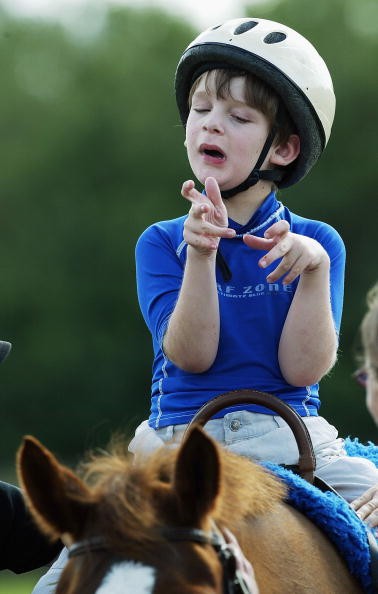 An autistic boy rising a horse. 